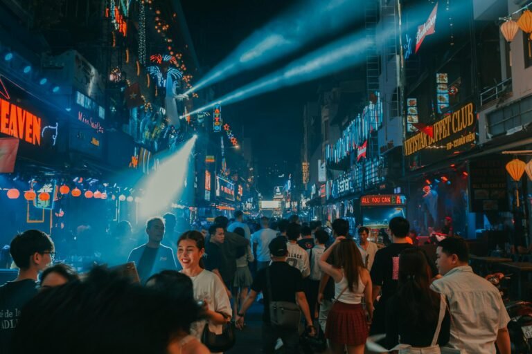 Experience the lively city nightlife with crowds and neon lights illuminating the streets at night.